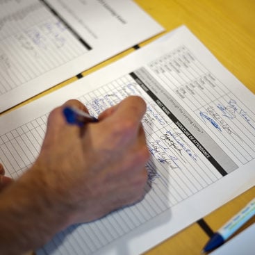 photo of someone adding their name to a sign-in sheet