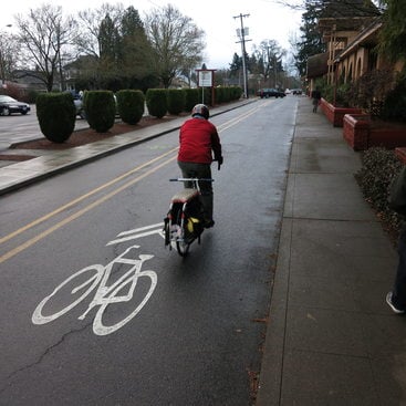 photo of a cyclist on a bike lane and a nearby pedestrian