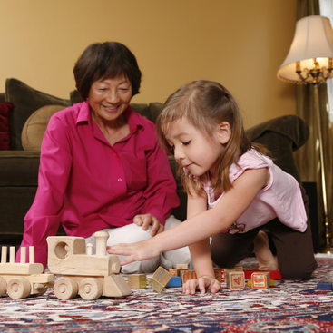 photo of a grandmother and child playing with a wooden train