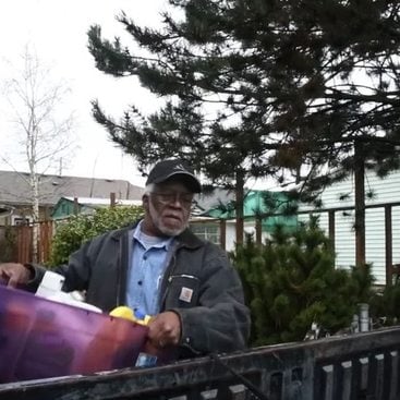 Man carrying tub of materials to be recycled.