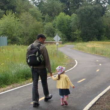 father and young daughter walk together on Fanno Creek Trail