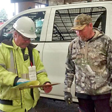 transfer station worker checking a clipboard while helping a customer