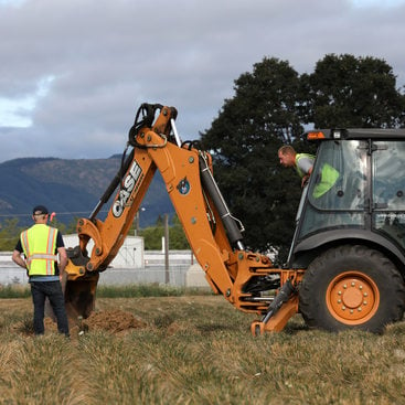 A tractor operator leans out of his tractor cab to converse with two co-workrs at a test site in rural  Washington County.