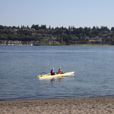 two people in a kayak paddle out from the shore of the Columbia River at Broughton Beach