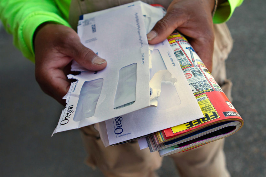 hands hold a stack of opened envelopes and junk mail