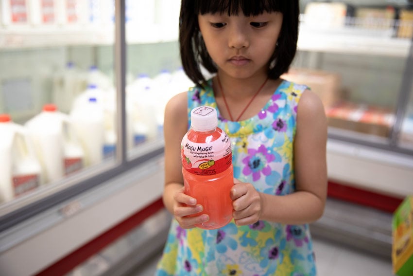 a young girl holds a plastic juice bottle 
