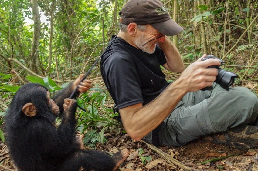 photographer and filmmaker Gerry Ellis seated on the forest floor with a chimpanzee