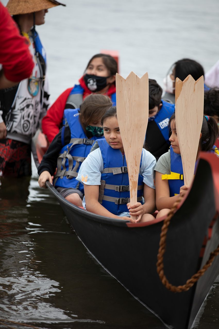 young people in life jackets sit patiently in a canoe on the Columbia river