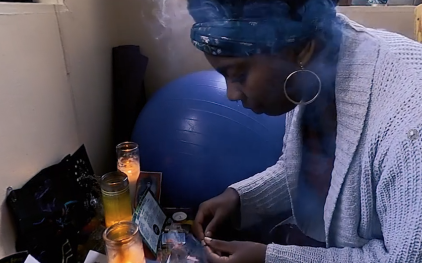 screenshot from film showing a person in front of a dresser with candles