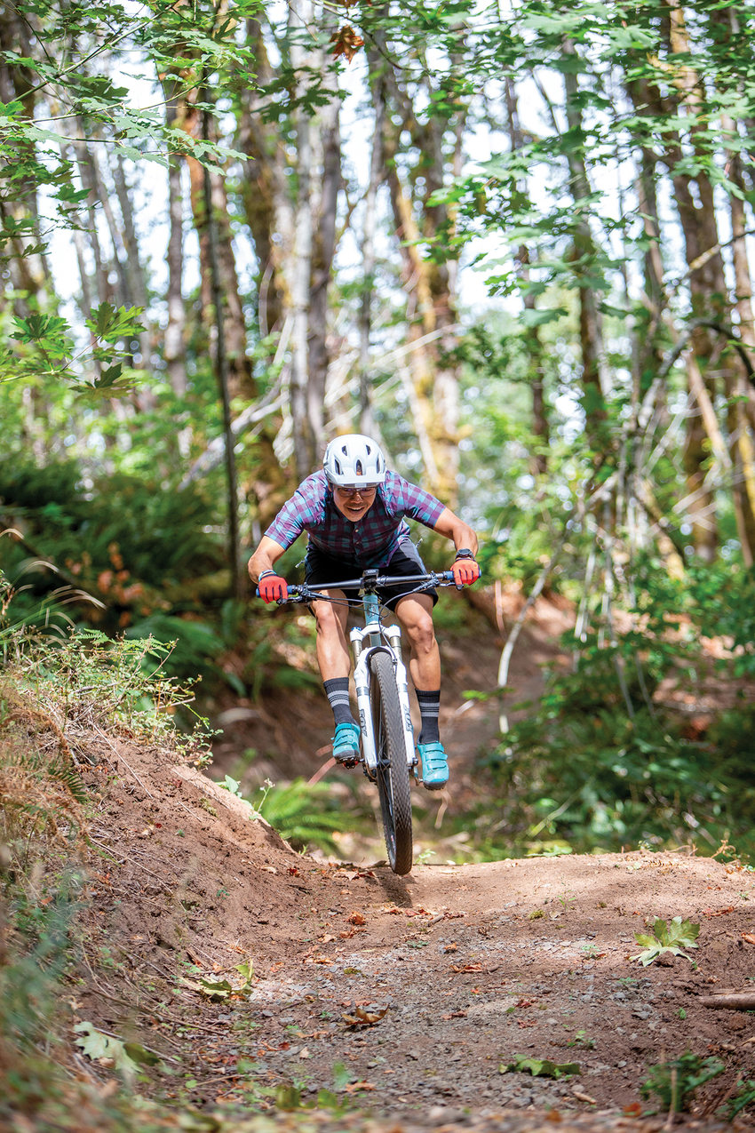 A mountain biker jumps over a small mound on a dirt path in Newell Creek Canyon Nature Park.