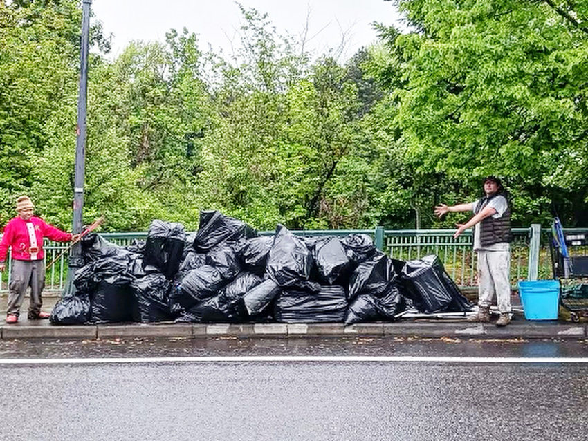 An image of two people separated by a large pile of garbage bags.