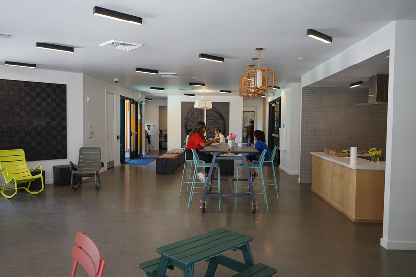 Interior of community space with colorful tables and chairs throughout the room and two people sitting at a table