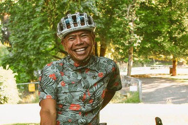 Will Cortez smiling outdoors, wearing a bike helmet and Hawaiian shirt