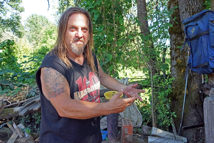 Man with long hair and beard wearing Harley-Davidson shirt and gesturing