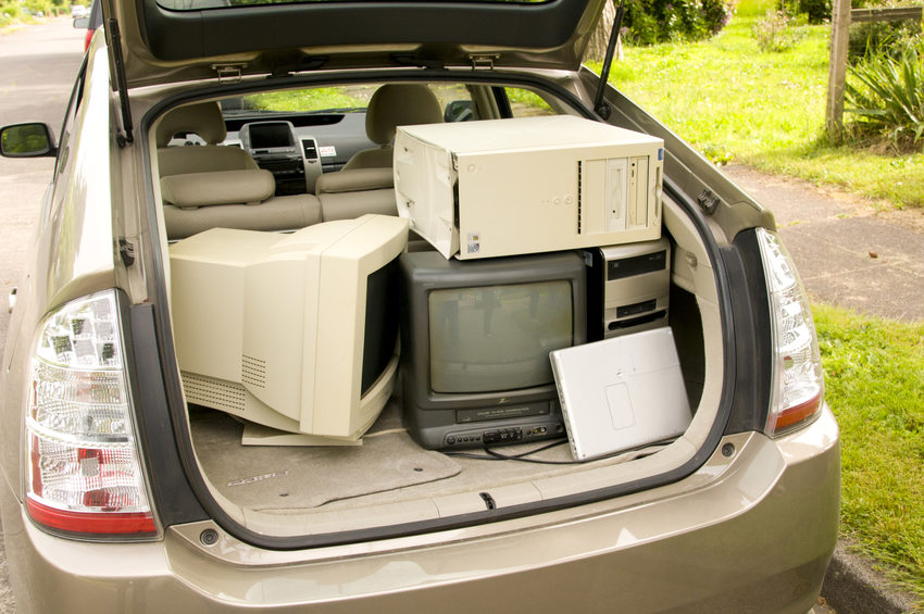 The back of tan car is open, revealing computers and monitors on the way to being recycled by an electronics recycler