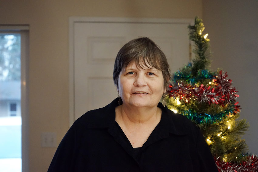 Woman with short hair in black shirt in front of Christmas tree