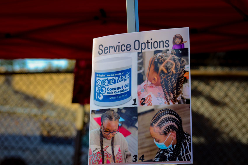 A sign for hair braiding service options at the Afro-topia pop-event showing attendees options for getting their scalped greased or style their hair in twists or braids