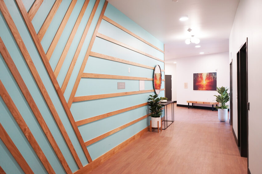 Apartment hallway with geometric design on wall to the left and a painting of a sunset on the far wall.