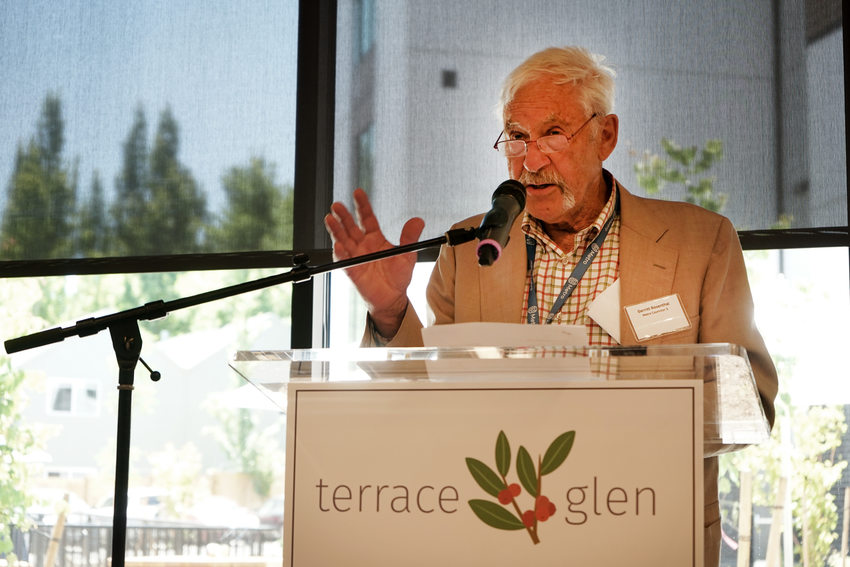 Elder man with white hair and mustache speaking at a podium with a sign reading "Terrace Glen"