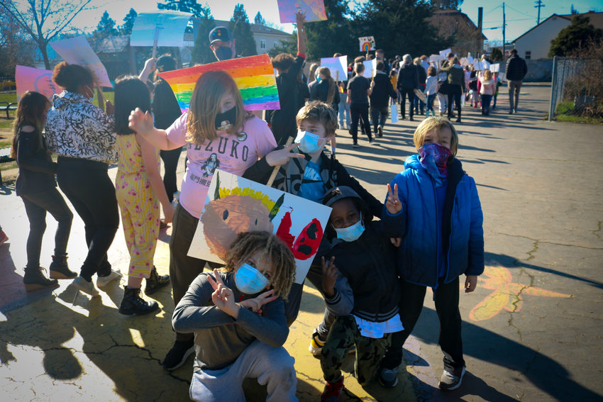Vestal School students of various backgrounds pose for a photo during a rally where people are marching with colorful signs