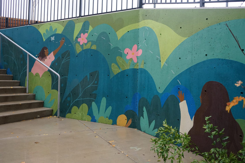 Colorful mural by a stairwell depicting children and nature. 