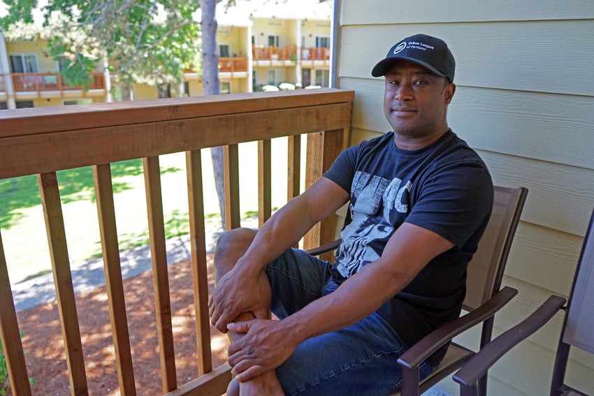 Man sitting on apartment complex porch.