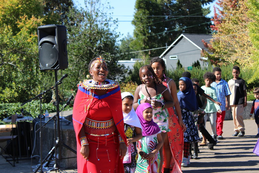 A group of people of various ages and cultural backgrounds dancing in a line in the park