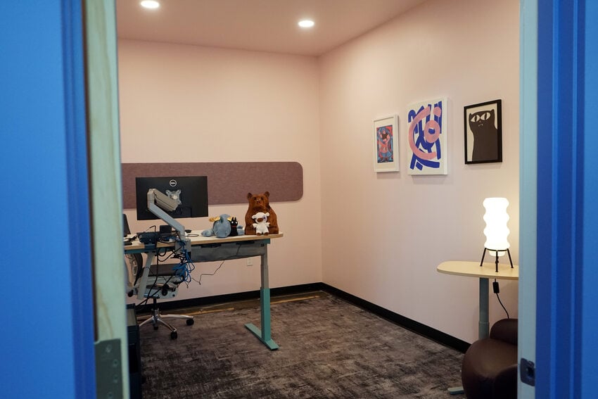 Office with bear on desk, framed art and a whimsical lamp.