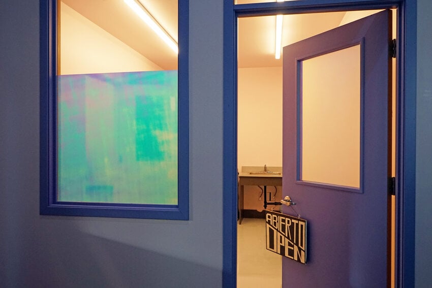 Office with purple exterior walls and open door. A sign hanging from the doorknob reads "Open/Abierto."