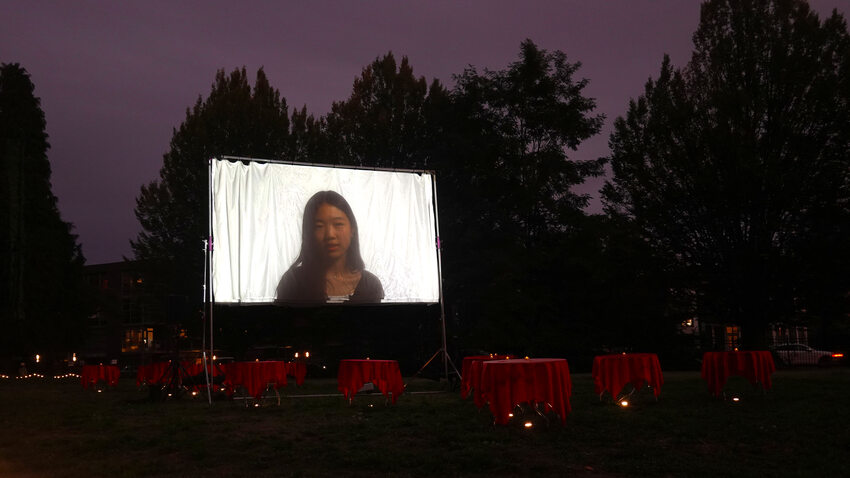 A wide view of Block 14 with the Serenading the Departed projection screen, tables and audience in the background.