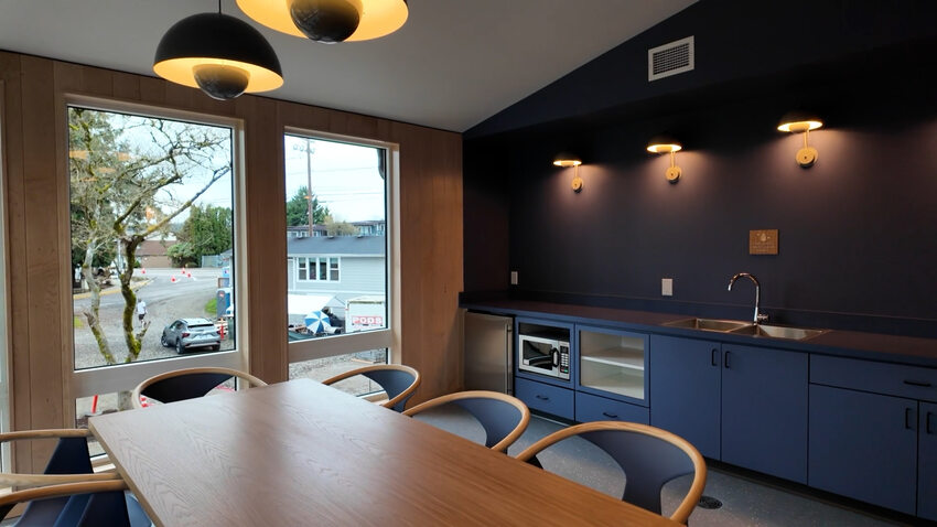 Community kitchen with sink bay in the background and communal table in the foreground. 