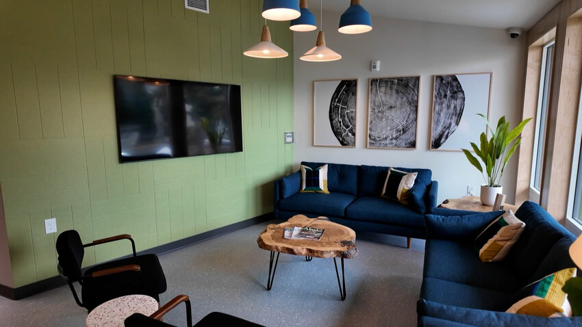 Community room with blue sofas and a TV mounted on the wall.