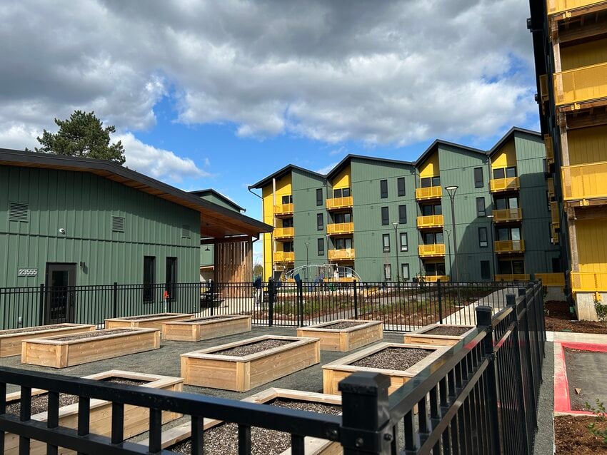 Multi-building apartment complex with raised garden beds in foreground.