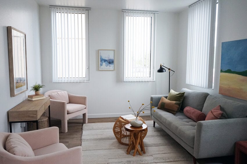 Living room with light colored furniture and three windows.