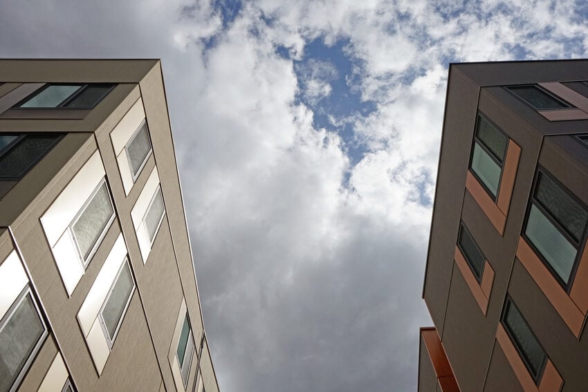 Two apartment buildings from a low angle with sky and clouds.