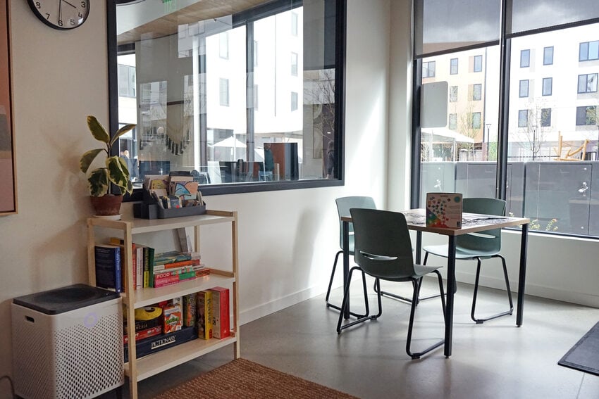 Game corner with table and chairs and a shelf of games.