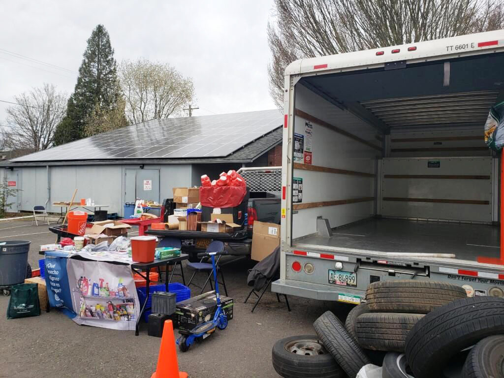 An image of an open truck next to a pile of tires and table to collect medicine.