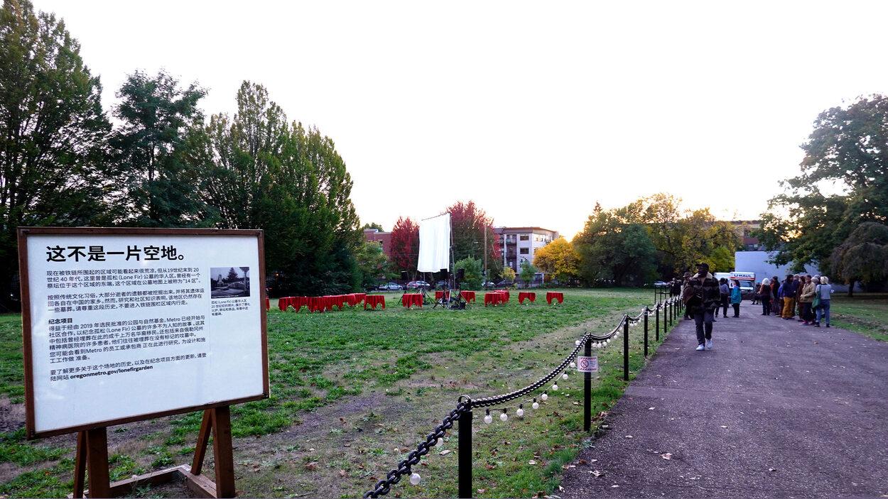 In the foreground, there is a sign in Chinese that explains the history of Block 14. In the background, there is a projection screen, tables with red tablecloths, and event attendees gathered on the pathway.