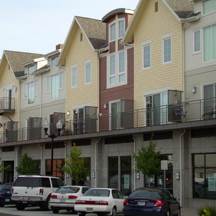 a photo of rows of townhomes above businesses and parking