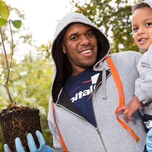 father holding his son and a sapling tree to be planted