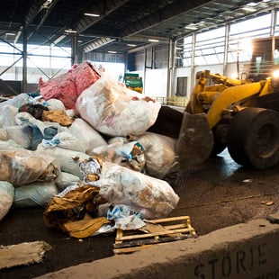 photo of a backhoe moving garbage at a transfer station