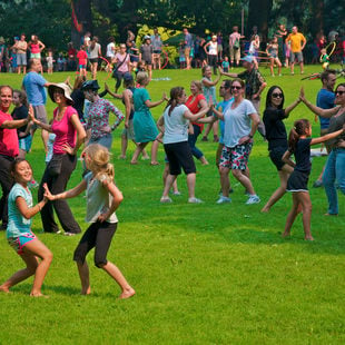 photo of men, women and children dancing in grassy area at Sunday Parkways