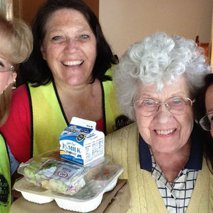food recipient poses with volunteers