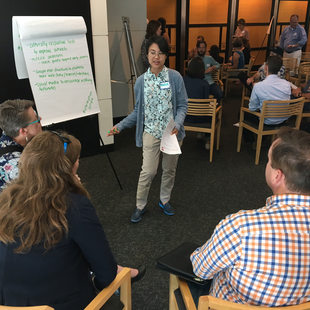 woman speaking to people and writing comments on a flipchart during a meeting in Metro Regional Center