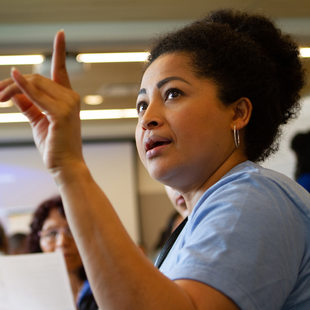 a woman raises her hand while addressing her group