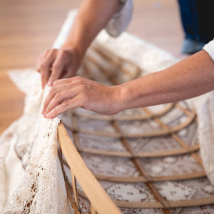 Close-up of hands adding lace "skin" to a wooden boat frame.