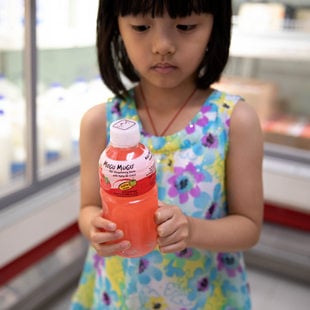 a young girl holds a plastic juice bottle 