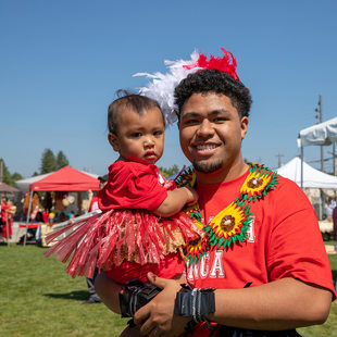 A young Tongan man holds a toddler