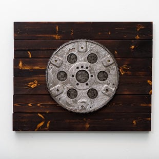 A round piece of metal, etched and mounted on wood