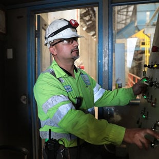 a man in a hard hat monitors a computer screen